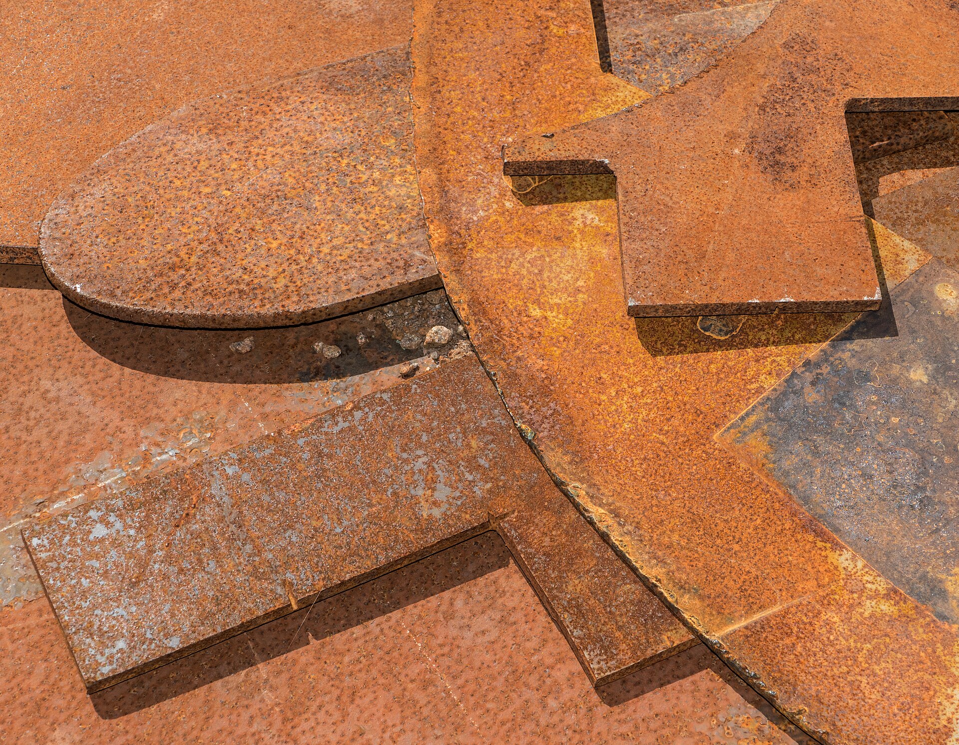 Close-up of corroded structural steel plate with rust, pitting, and coating breakdown